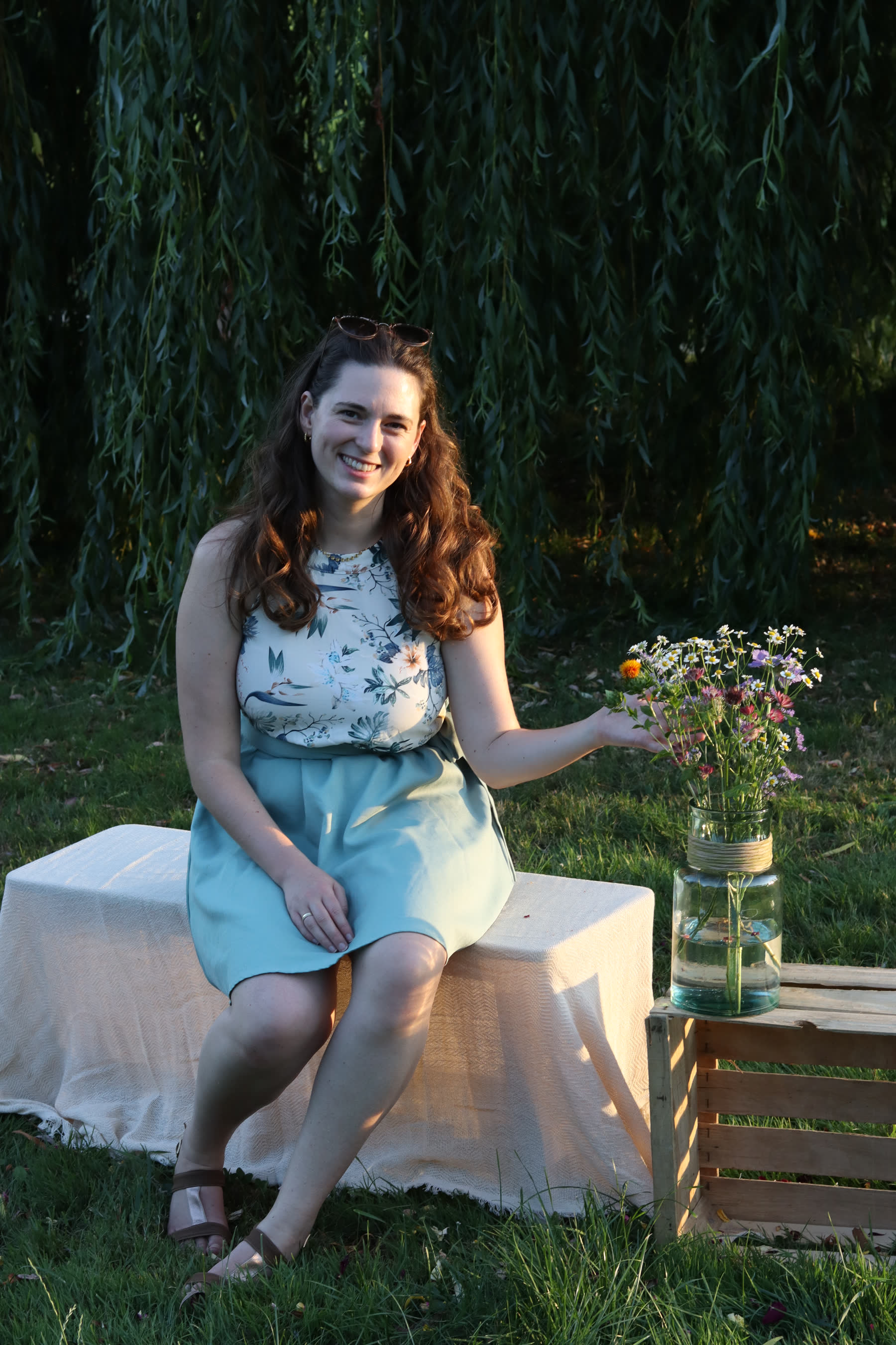 Jana Oettlin sitzt ruhig im Garten neben Blumen